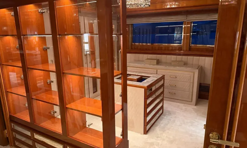 Isabell Princess of the Sea: Walk in wardrobe with lit glass cabinets, a central island and a dresser below windows