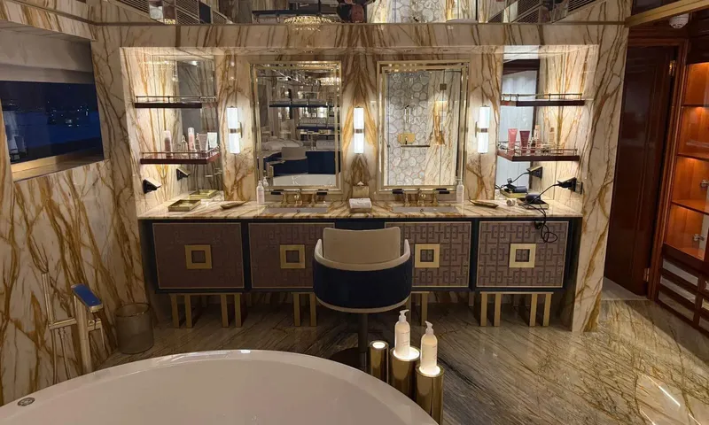 Isabell Princess of the Sea: Marble bathroom vanity with double sinks, mirrors and a stool, bathtub edge in front