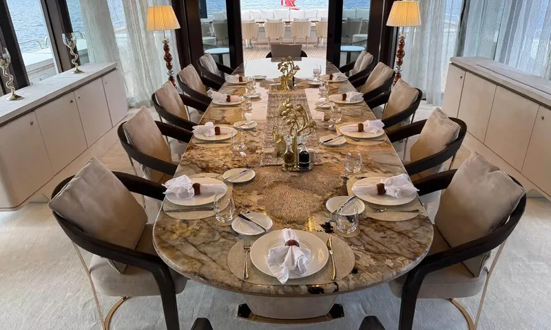 Isabell Princess of the Sea: Long marble dining table set for twelve with upholstered chairs and sea views beyond