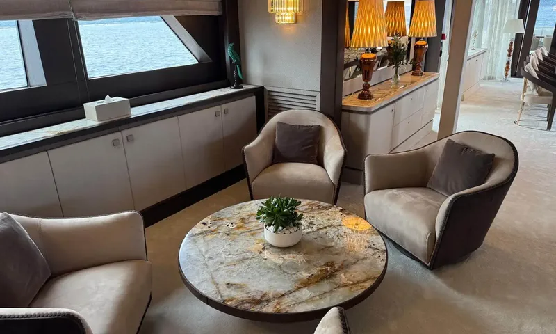 Isabell Princess of the Sea: Seating corner with beige armchairs around a round marble table beside sea view windows