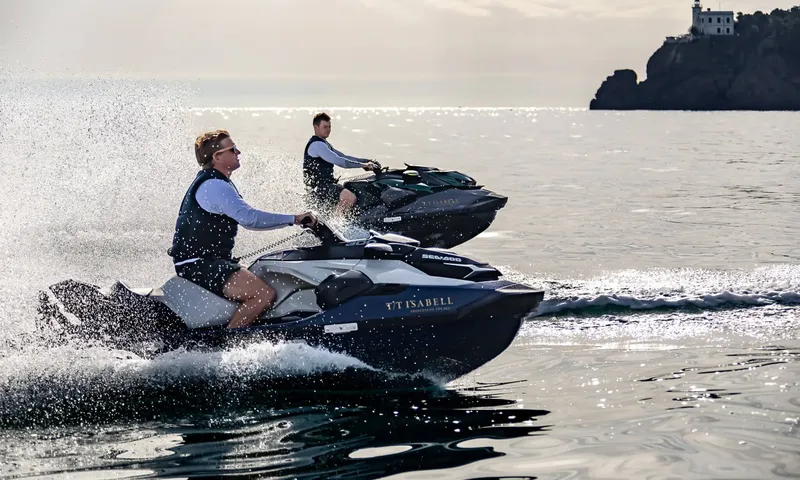 Isabell Princess of the Sea: Two riders on jet skis speeding across calm sea near a rocky headland