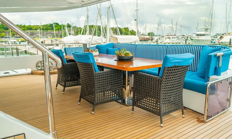 Indiana: Outdoor dining table with wicker chairs and blue cushions on a teak deck in a marina