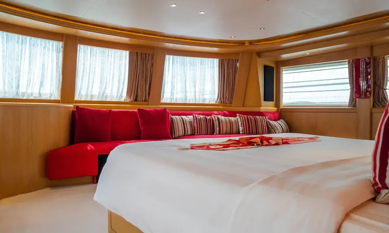 Indiana: Bed facing a red window seat with striped cushions under curtained windows
