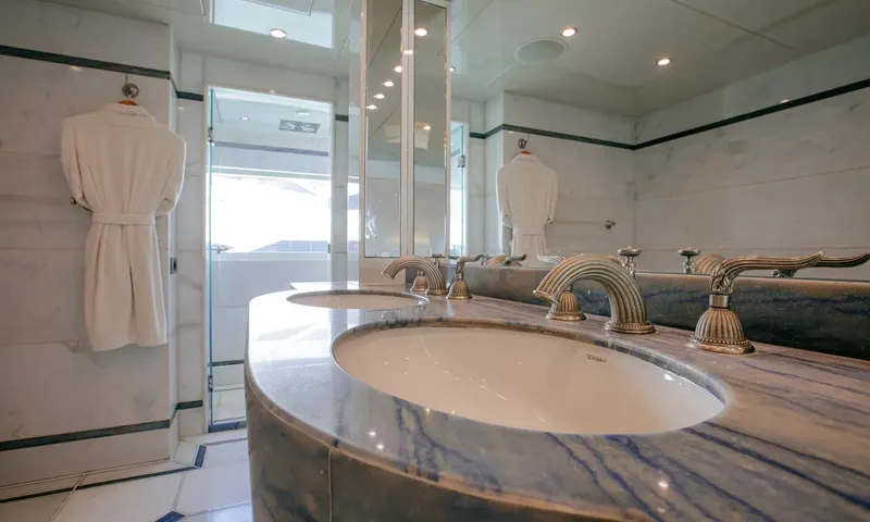 Indiana: Double basin vanity in blue veined stone with bathrobes hanging nearby