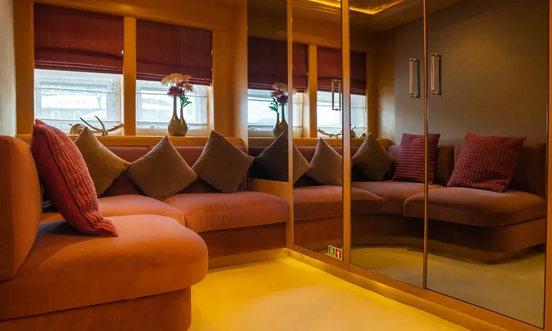 Indiana: Curved sofa with cushions beneath windows next to mirrored wardrobe doors