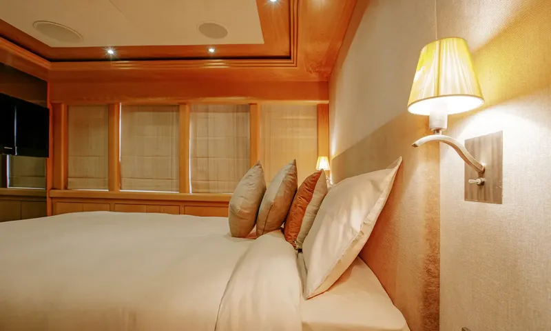 Indiana: Double bed with cushions beside a wall lamp and shaded windows