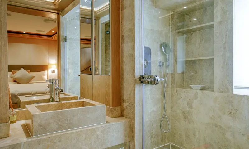 Indiana: Beige stone bathroom with a square basin and glass shower with handheld head