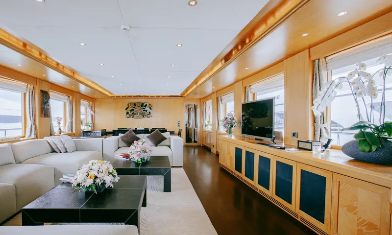 Indiana: Long saloon with sofas, coffee tables, orchids and a dining area in the background