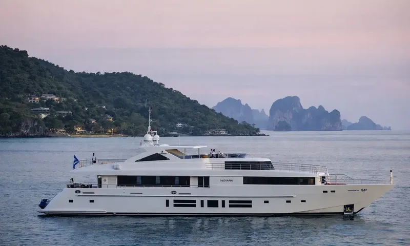 Indiana: White yacht at anchor at dusk with green hills and rocky islands behind
