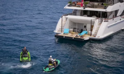 Nela: Two people on jet skis approaching the yacht's stern platform with lounge chairs