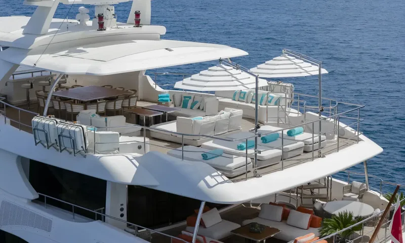 Nela: Upper deck with sunpads, white sofas, dining table and umbrellas above the sea