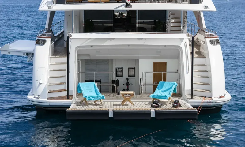 Nela: Stern swim platform with two blue towelled loungers, side stairs and small gym area