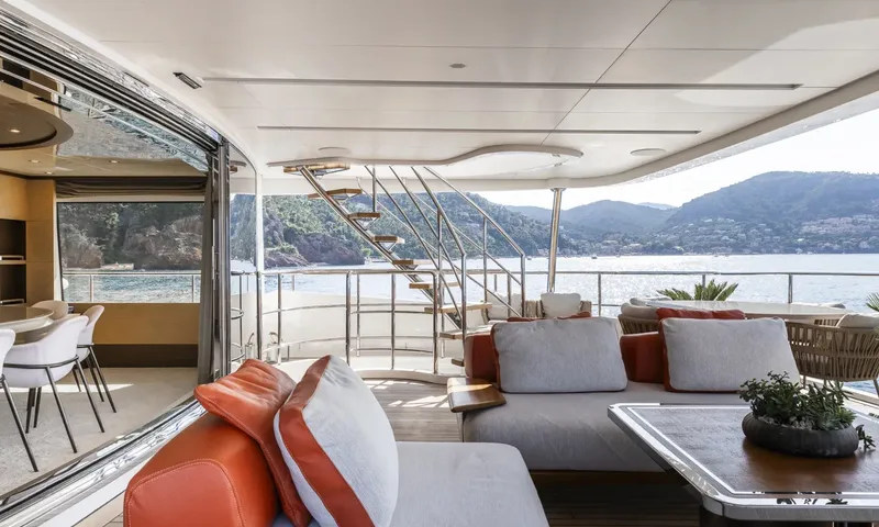 Nela: Aft deck lounge with orange cushions, staircase and glass doors to dining area