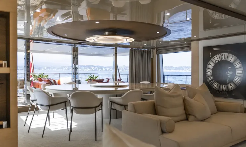 Nela: Round white dining table with chairs under a circular ceiling light near windows