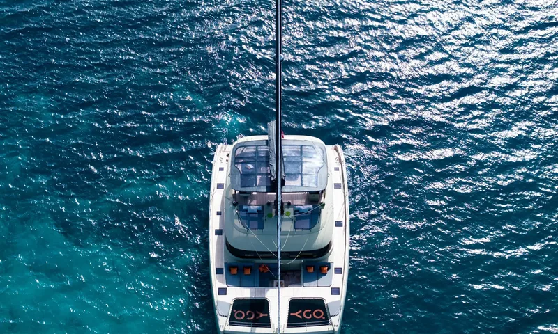 YGO: Overhead view of a catamaran on sparkling blue water with bow nets and flybridge