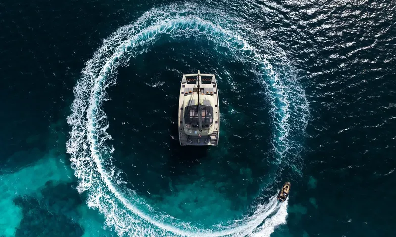 YGO: Top down view of a catamaran inside a circle of wake made by a small tender