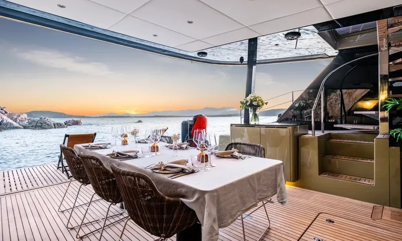 YGO: Set dining table on the aft deck with wicker chairs and a sunset sea view