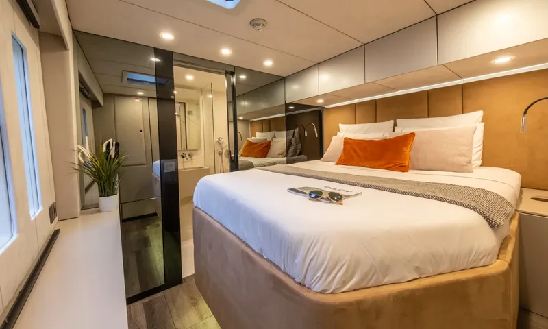 YGO: Cabin with large bed, orange cushion and sunglasses, ensuite visible through glass door
