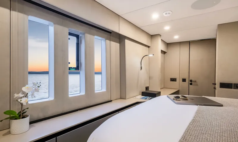 YGO: Cabin with bed foot, orchid and hull windows showing a sunset over the sea