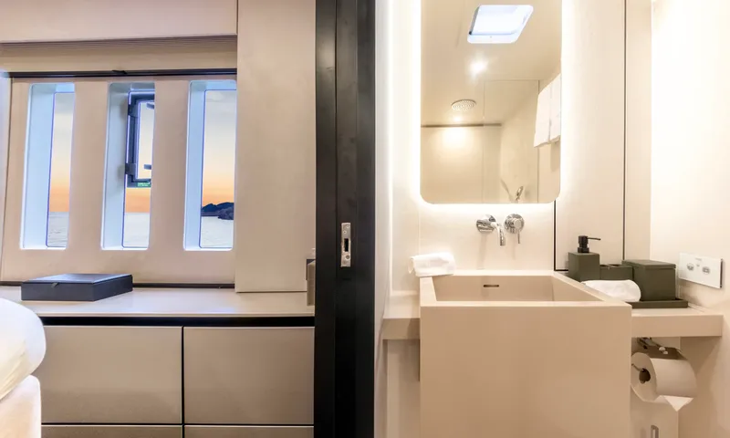 YGO: Ensuite washbasin with backlit mirror beside cabin windows looking out to sea