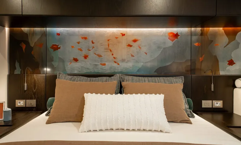 Hu-Lysse: Bed with cushions beneath a backlit painted panel of red leaves on blue