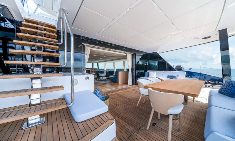 Hu-Lysse: Shaded aft deck with teak floor, wooden dining table, sofas and stairs up to the top deck