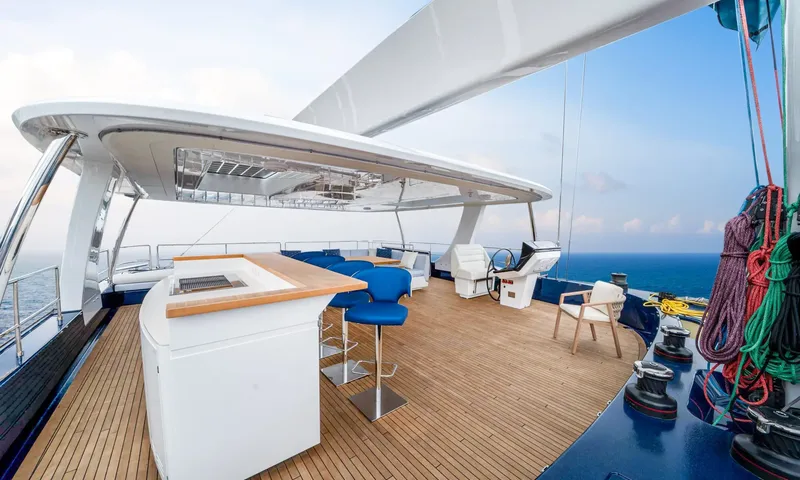 Hu-Lysse: Flybridge with teak deck, bar with blue stools, helm station, hardtop and coiled ropes