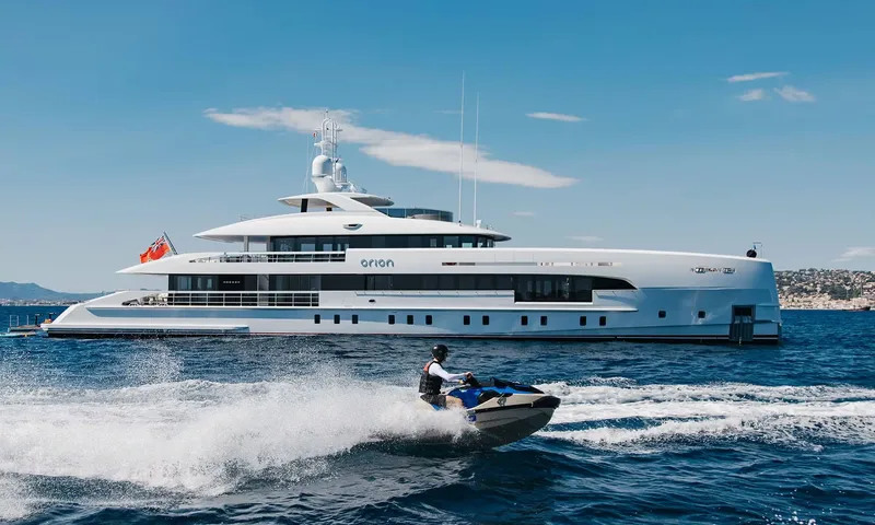 Orion: Rider on a jet ski speeding past a white motor yacht at anchor