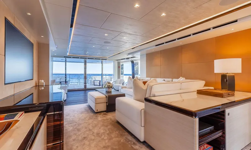 Orion: Lounge with white sofas, wall screen and glass doors opening onto the aft deck