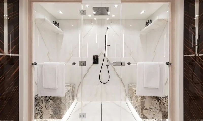 Orion: Glass enclosed marble shower with rain head, benches and white towels