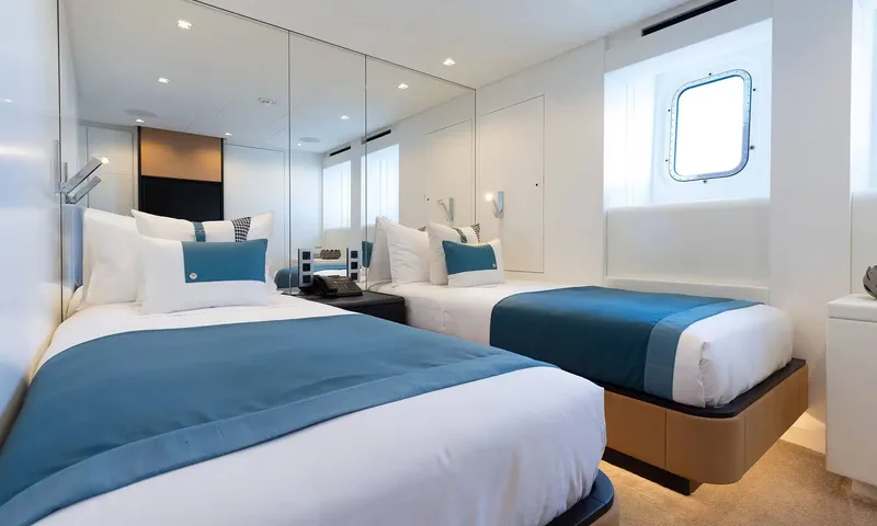 Orion: Twin cabin with two single beds, blue throws and a porthole