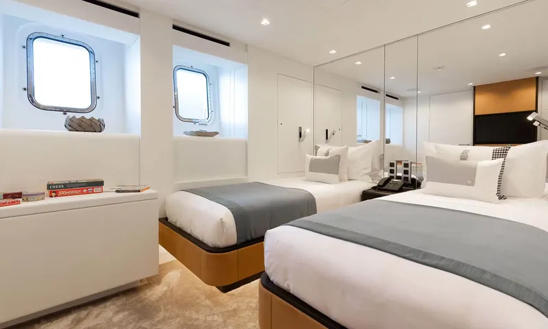 Orion: Twin cabin with two single beds, grey throws, portholes and board games
