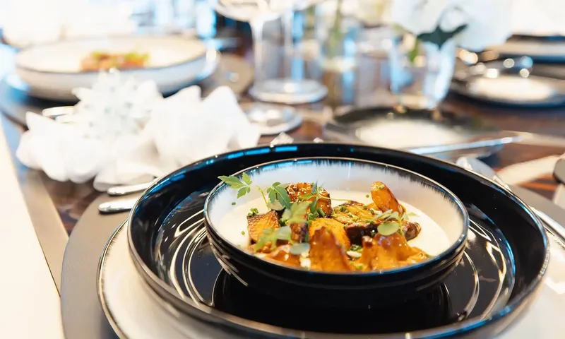 Orion: Plated dish of roasted mushrooms with herbs in a dark bowl on a set table