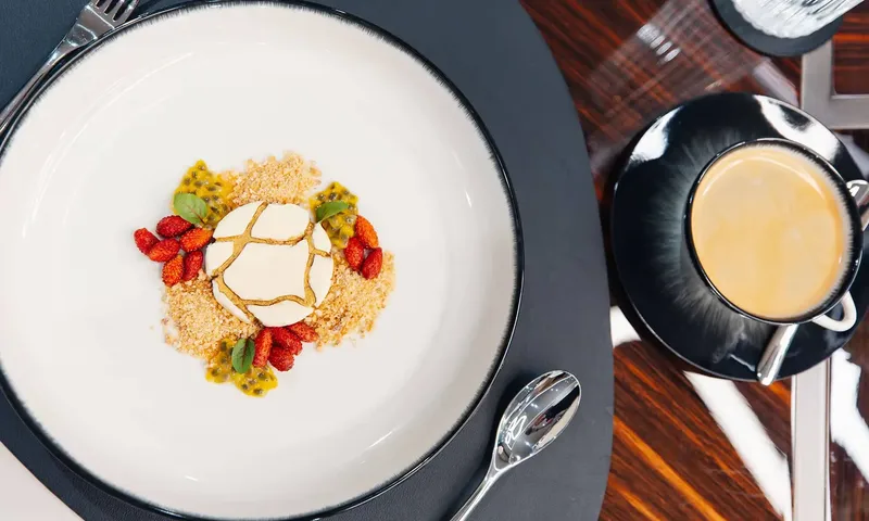 Orion: Overhead view of a plated dessert with berries and passion fruit beside a coffee cup