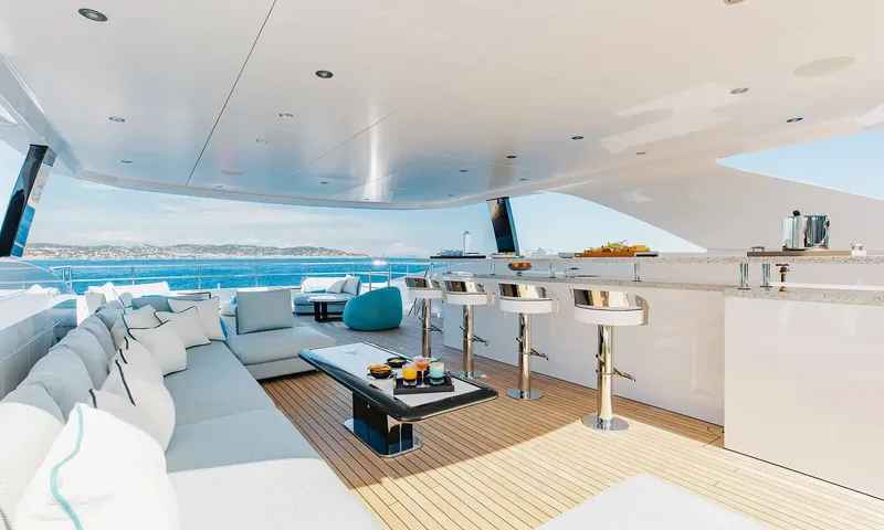 Orion: Shaded upper deck with long sofa, coffee table, bar stools and bar overlooking the sea