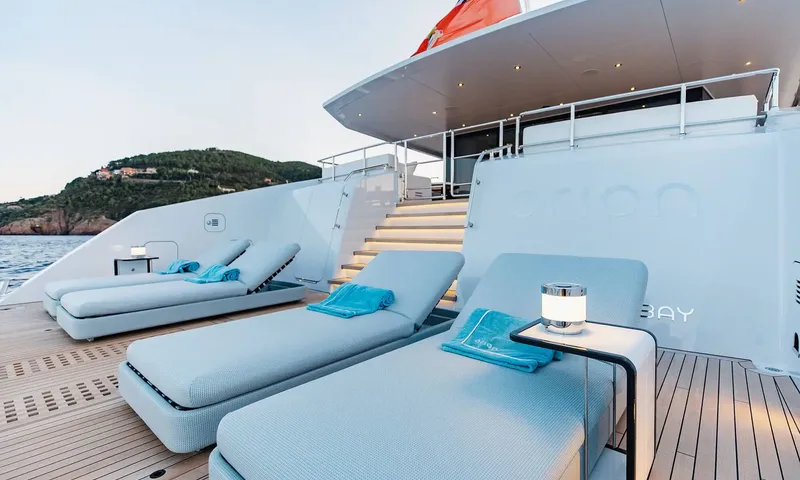 Orion: Stern deck with cushioned sun loungers, towels and stairs leading to the upper deck