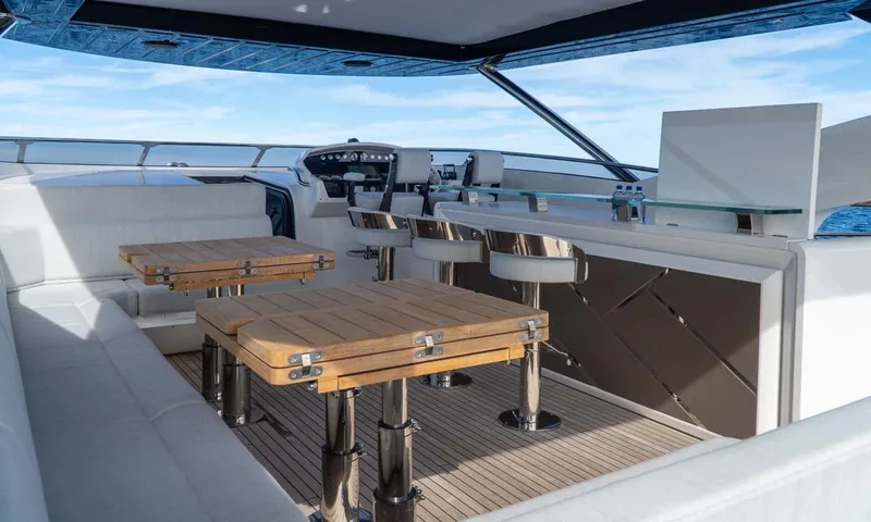 Nigora: Flybridge helm station with bar stools, folding teak tables and white seating