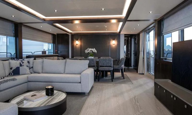 Nigora: Open plan saloon with grey sofa, round coffee table and dining area beyond