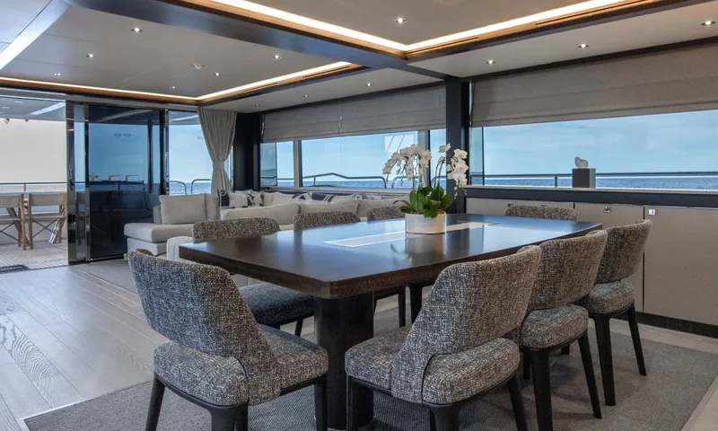 Nigora: Indoor dining table with eight upholstered chairs and orchids beside large windows