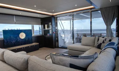 Nigora: Saloon with grey sectional sofa, moon artwork and glass doors opening to the aft deck