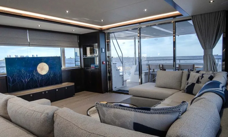 Nigora: Saloon with grey sectional sofa, moon artwork and glass doors opening to the aft deck