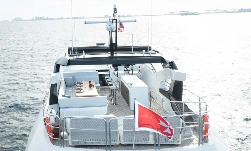 Nigora: Elevated view of the yacht's upper deck with sofas, dining table and bar on open water